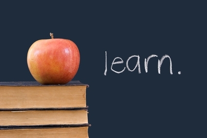 "learn" written on blackboard with apple, books